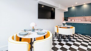 Una cocina moderna con armarios verde azulado, un televisor negro montado en la pared y un suelo a cuadros.