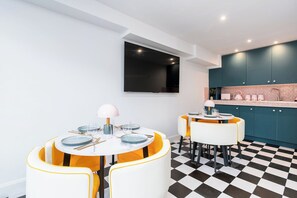 A modern kitchen with teal cabinets, a black TV mounted on the wall, and a checkered floor. - Kirkstone Pass Mountain Rooms (Windermere)