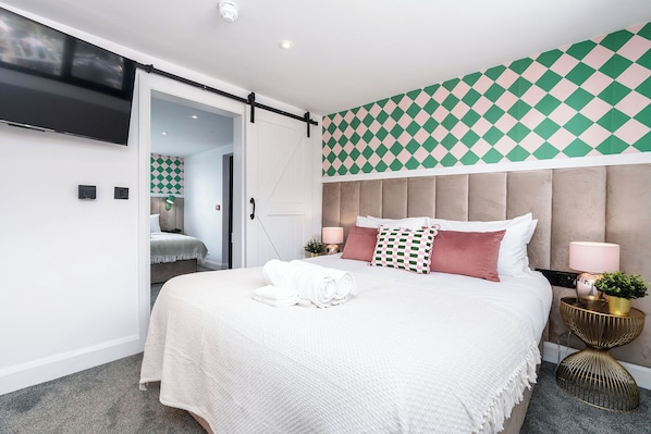 Ein modernes Hotelzimmer mit einem großen Bett, einem flachbildfernseher an der Wand und einem Wandteppich mit Muster.