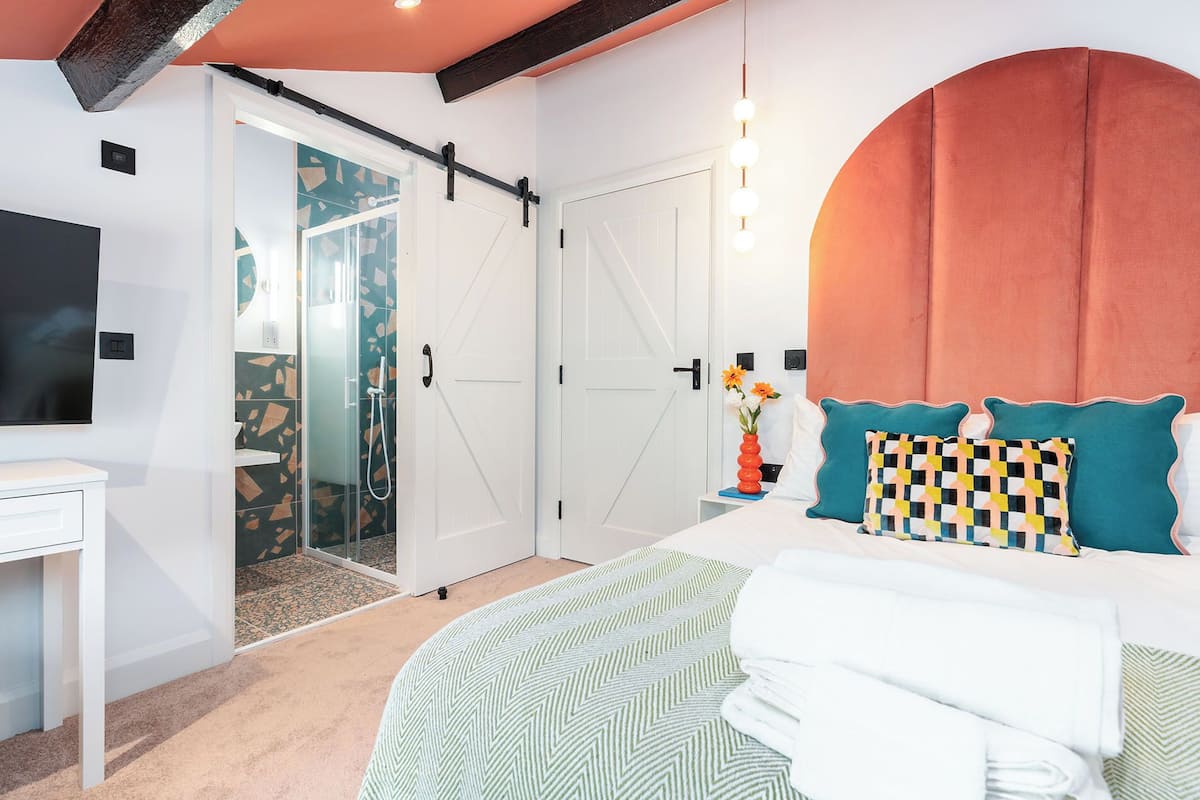 A hotel room with a bed, a desk, a TV, a sliding door, and a bathroom.
