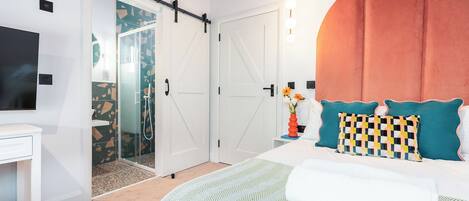 A hotel room with a bed, a desk, a TV, a sliding door, and a bathroom.