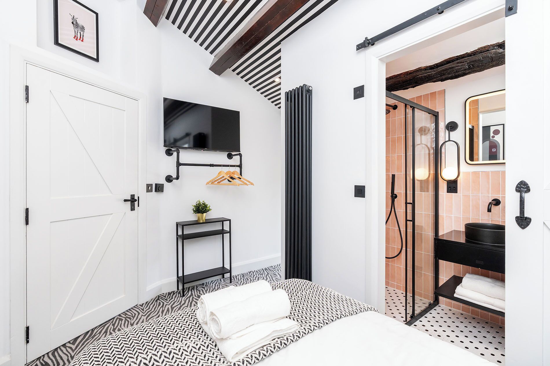 A modern bathroom with a black and white patterned floor, a black sink, and a mirror with a decorative frame.