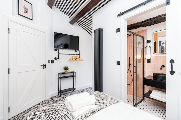 A modern bathroom with a black and white patterned floor, a black sink, and a mirror with a decorative frame.