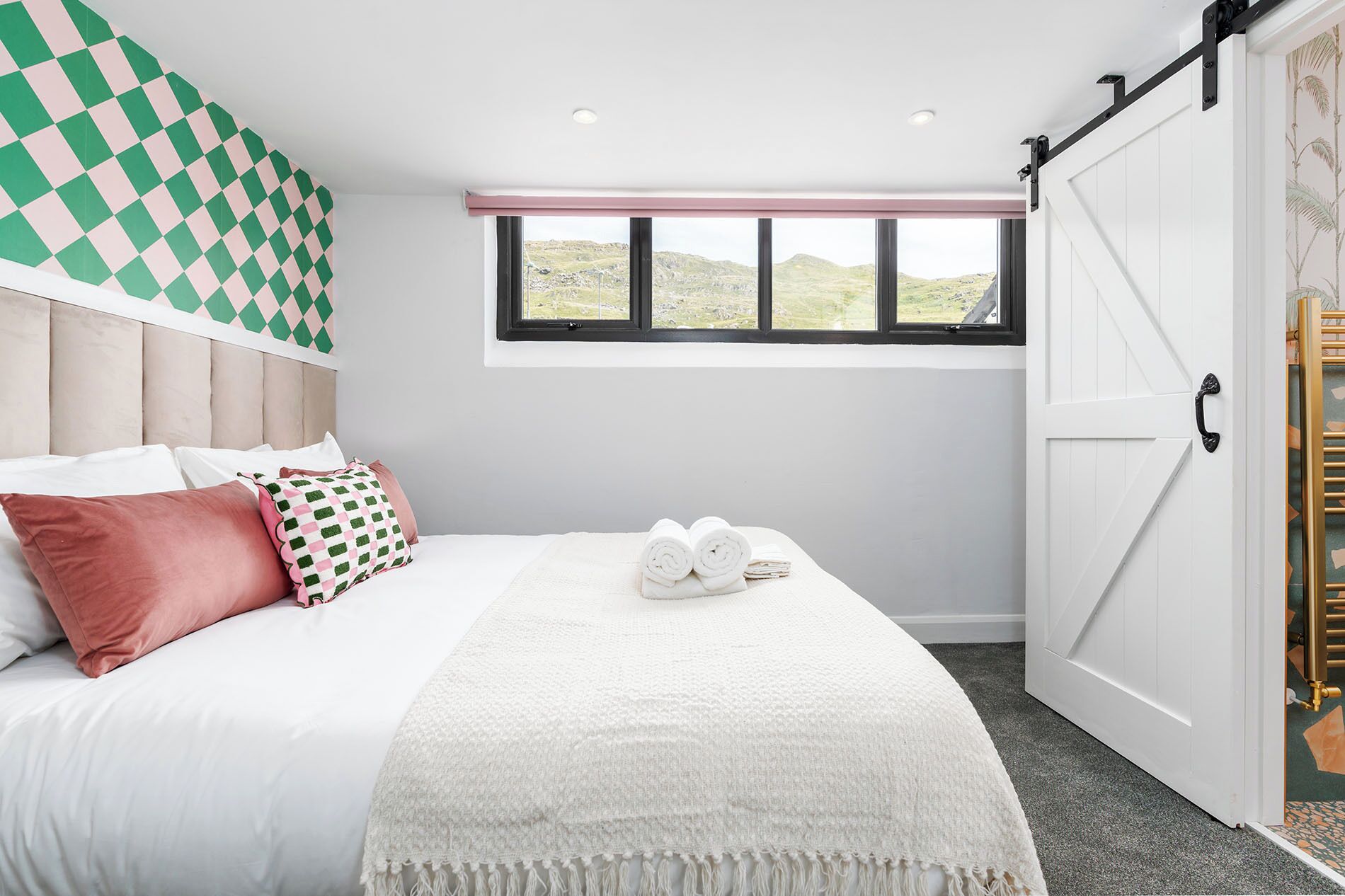 A bedroom with a bed, pillows, a window, and a sliding door.
