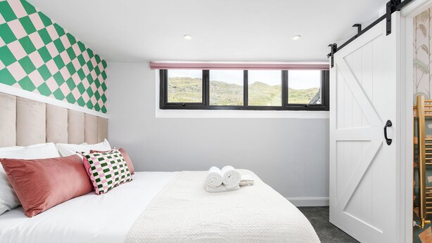 Une chambre à coucher avec un lit, des oreillers, une fenêtre et une porte coulissante.