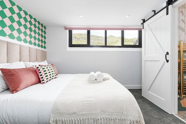 A bedroom with a bed, pillows, a window, and a sliding door.