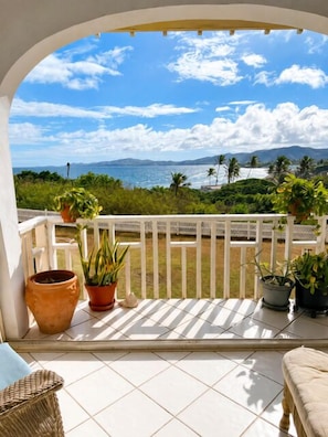 A balcony with a view of the sea, potted plants, and a white fence. - Welcome to Island Breeze, Your Oceanfront Escape in Beautiful St. Croix (Christiansted)