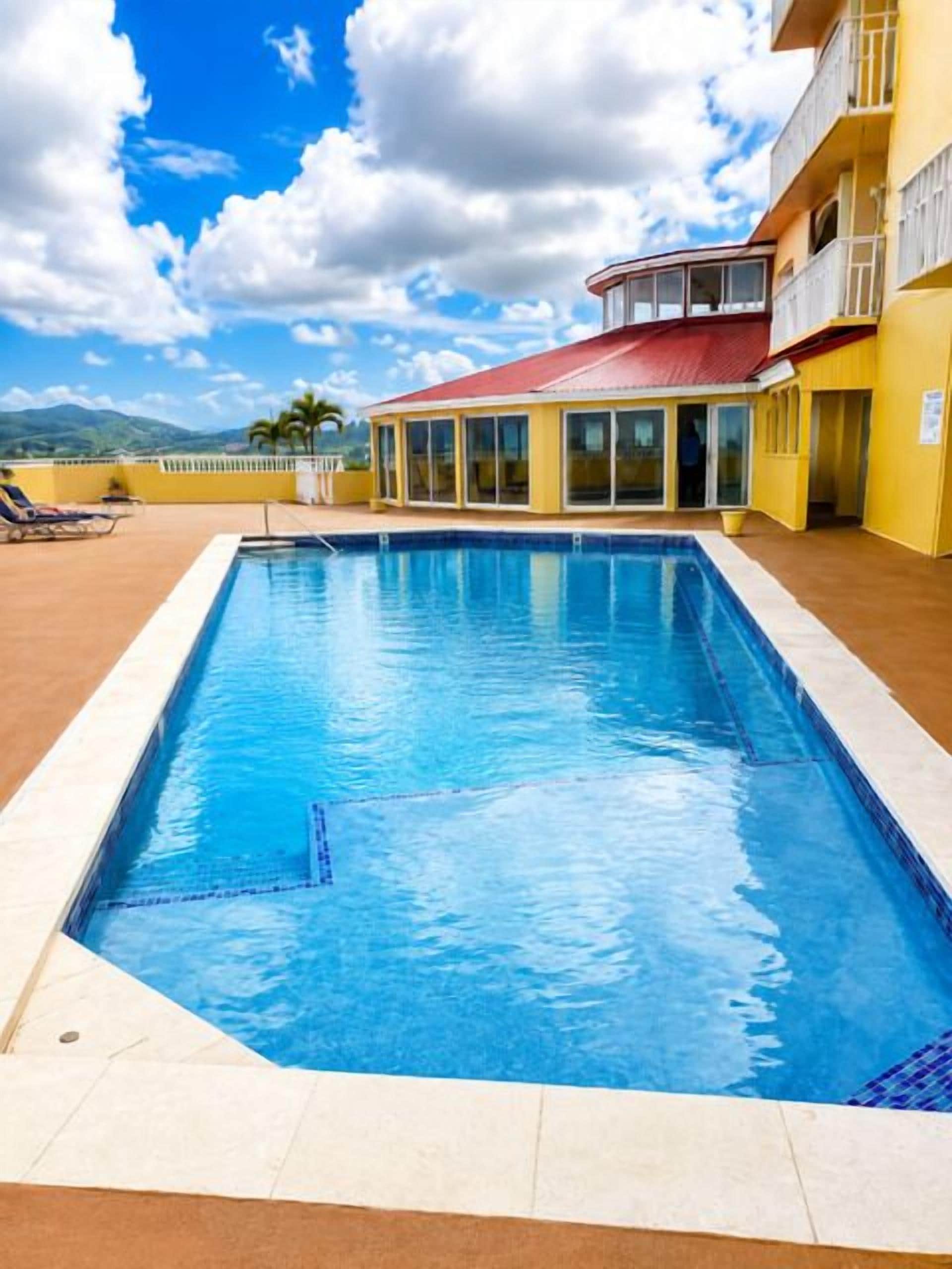 Une piscine rectangulaire à l’eau d’un bleu limpide, entourée d’une terrasse carrelée.