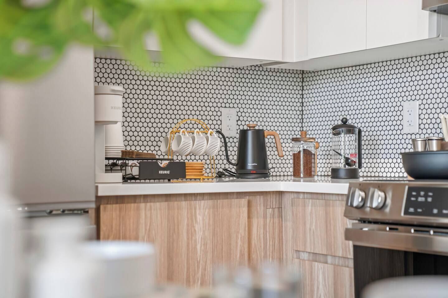 A modern kitchen with a coffee maker, kettle, and a coffee grinder on the counter.