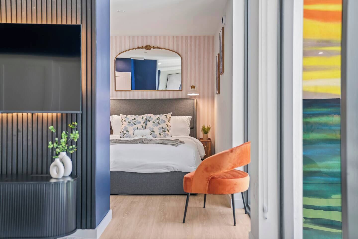 A modern bedroom with a bed, a mirror, a nightstand, and a chair.