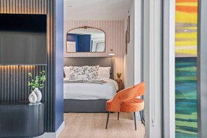 A modern bedroom with a bed, a mirror, a nightstand, and a chair. - 5 Mins to Beach | Pickle ball | Resprt Style Pool | Free Parking (Fort Lauderdale)