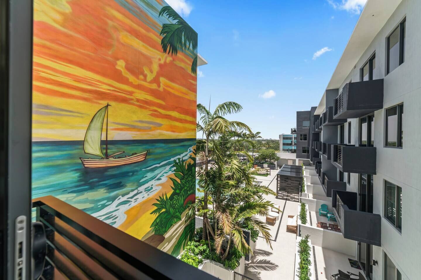 A modern building with balconies and a view of a painted sunset scene.