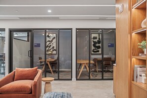 An office space with glass partitions, a wooden desk, a brown chair, and a small round table. - 5 Mins to Beach | Pickle ball | Resprt Style Pool | Free Parking (Fort Lauderdale)