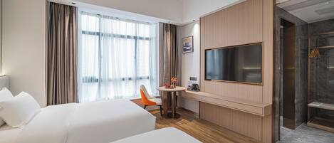 A hotel room with two beds, a TV, a small table with a chair, and a shower area.