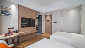 A hotel room with a bed, a desk with a chair, a television, and a wardrobe. - Poltton International Apartment (Zhanjiang Xuwen Chengdong Dadao) (Zhanjiang)