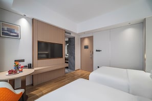 A hotel room with a bed, a desk with a chair, a television, and a wardrobe.