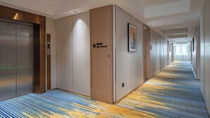 A hotel corridor with a patterned carpet, wooden panel walls, and a fire hydrant sign. - Poltton International Apartment (Zhanjiang Xuwen Chengdong Dadao) (Zhanjiang)
