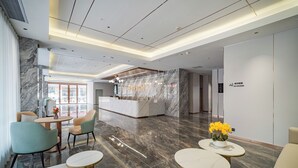 A modern hotel lobby with marble flooring, a reception desk, seating areas, and a 'No Smoking' sign. - Poltton International Apartment (Zhanjiang Xuwen Chengdong Dadao) (Zhanjiang)