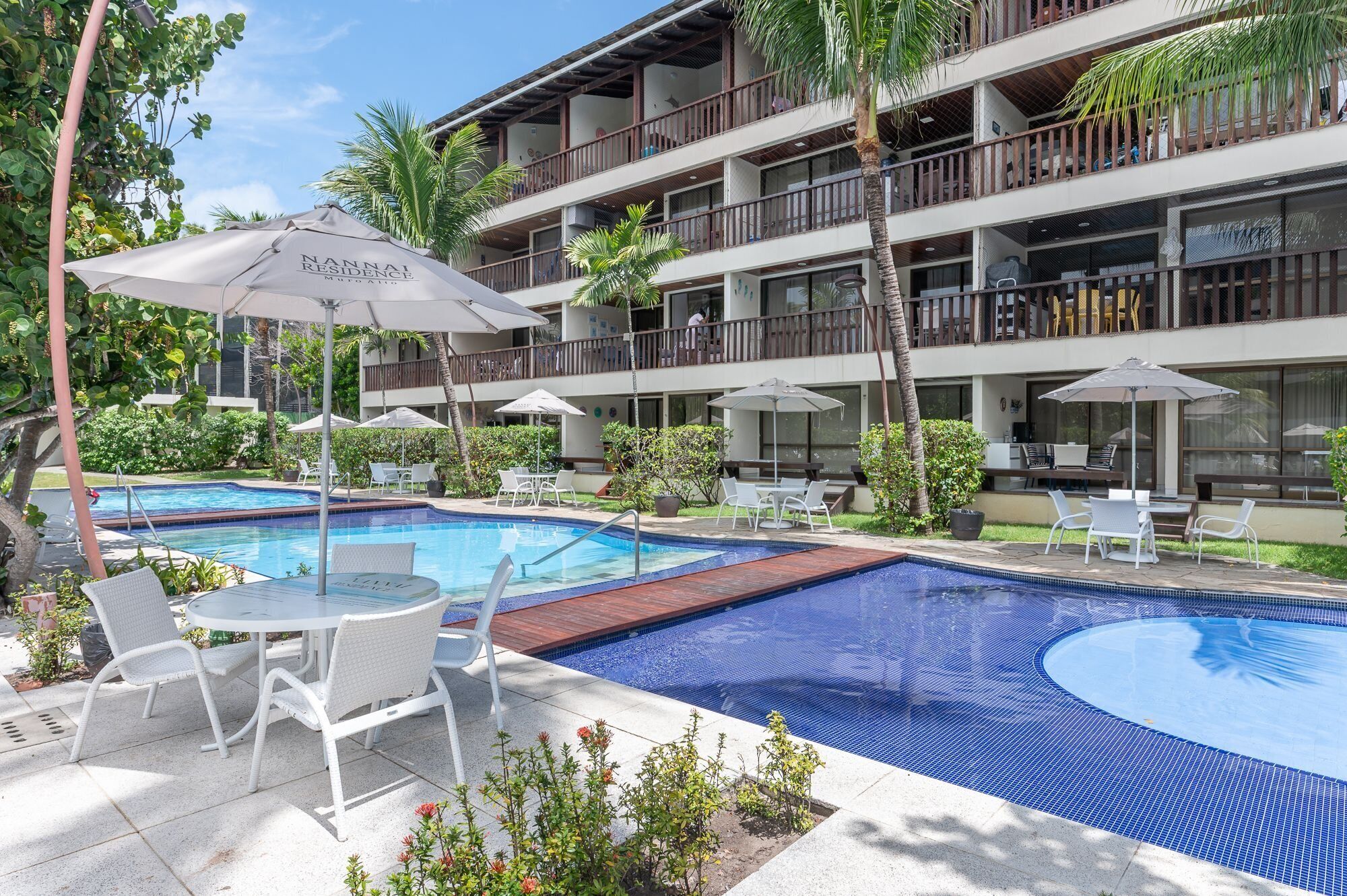 Un hotel con piscina, zona de estar exterior y varios balcones.