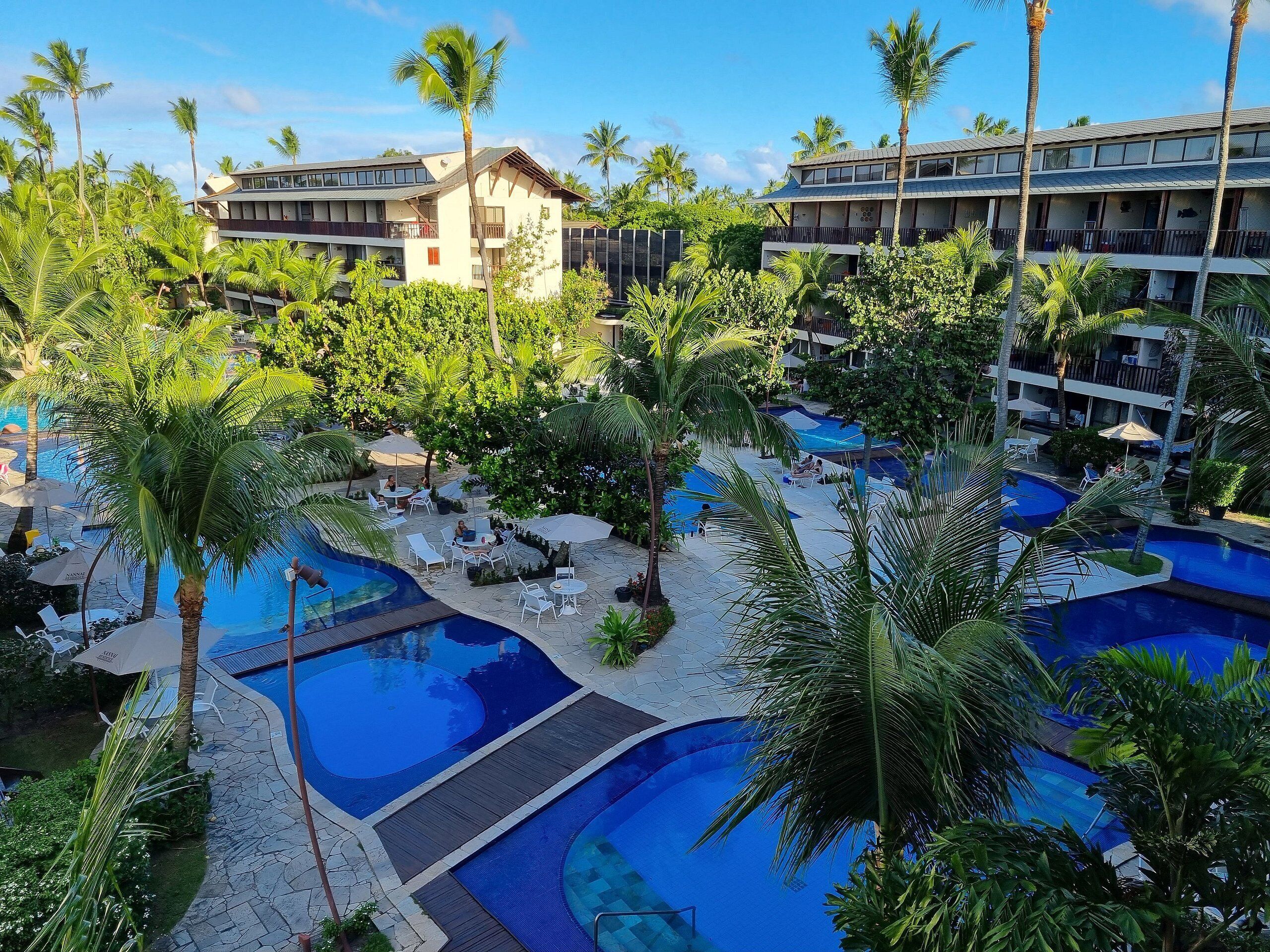 A resort with multiple swimming pools surrounded by palm trees and lounge chairs.