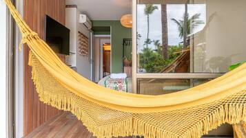 A hammock in a doorway, a television, and a view of palm trees through a glass door.