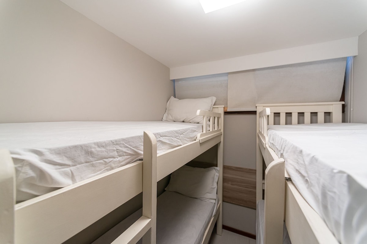 Ein Zimmer mit drei Etagenbetten, jeweils ausgestattet mit einer weißen Matratze und einem Kopfkissen.