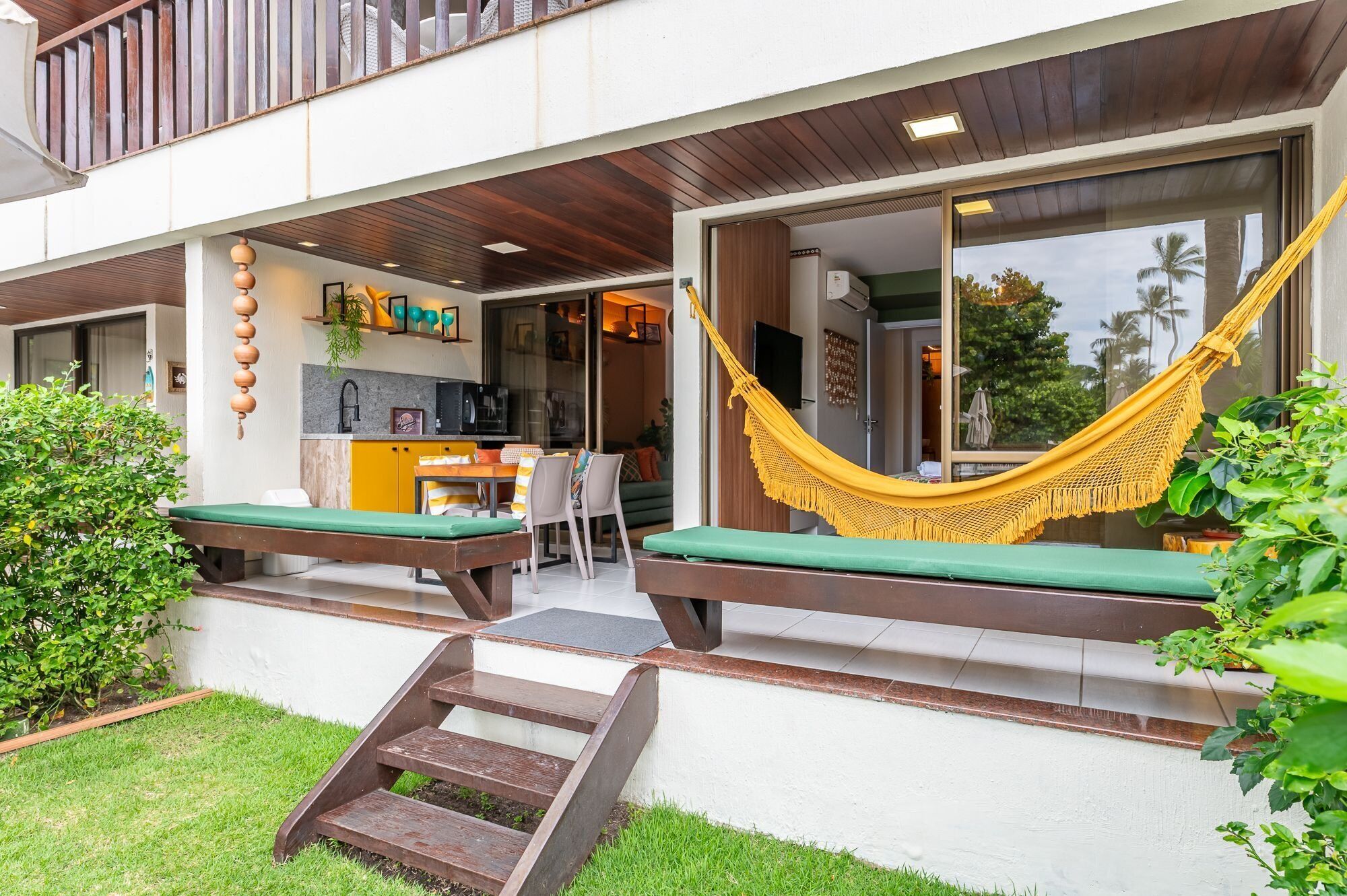 Un espacio al aire libre moderno con una hamaca, una mesita y un banco.