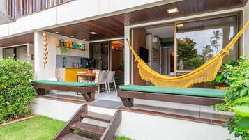 A modern outdoor seating area with a hammock, a small table, and a bench.