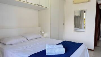 Quarto de hotel com cama, abajur, espelho e ar condicionado.