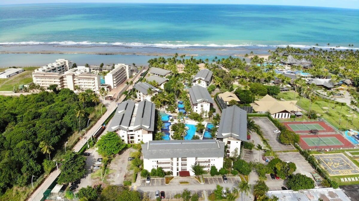 A resort with multiple buildings, a swimming pool, and a view of the ocean.