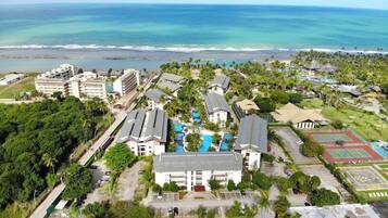 A resort with multiple buildings, a swimming pool, and a view of the ocean.