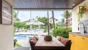 A dining area with a view of a pool and palm trees.