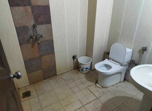 Un baño pequeño con inodoro, lavamanos y un cubo.