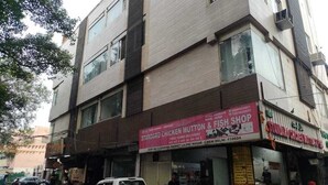 A multi-story building with a shop on the ground floor advertising chicken mutton and fish.