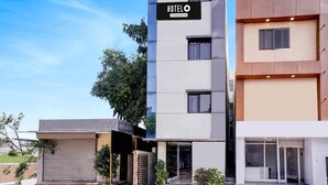 A modern hotel building with a prominent 'HOTEL' sign, a flat facade, and a gated entrance.