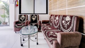 A living room with a sofa, two armchairs, a glass coffee table, and a large window.