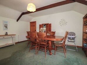 A dining area with a wooden table and chairs, a radiator, a small cabinet, and a baby high chair. - Honeysuckle (Newquay)