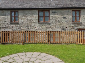 A stone building with three windows and a wooden fence. - Honeysuckle (Newquay)