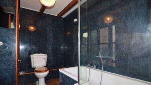 Et moderne badeværelse med toilet, badekar og bruser.