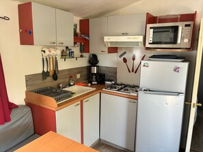 A compact kitchenette with a gas stove, a microwave, a refrigerator, and a sink. - Le Cabanon des Étangs by Sur la mer (Fréjus)