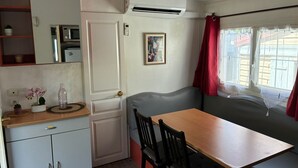 A compact kitchenette with a microwave, refrigerator, and a small cabinet. - Le Cabanon des Étangs by Sur la mer (Fréjus)