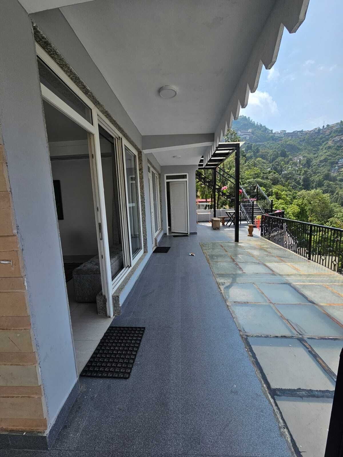 Un balcon fermé offrant une vue sur un paysage vallonné.