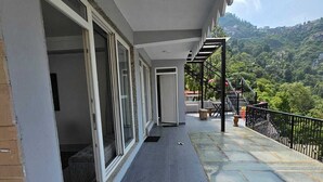 A covered balcony with a view of a hilly landscape. - Sukon House by Crimson Horizon (Mussoorie)