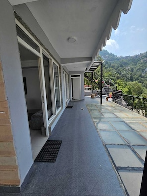 A covered balcony with a view of a hilly landscape.