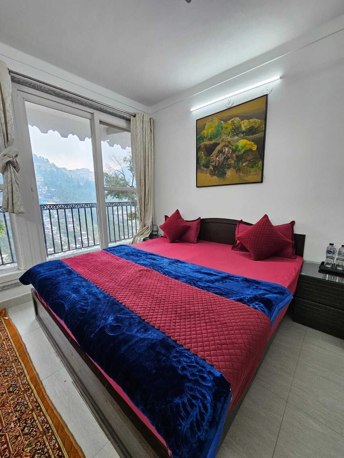 Un dormitorio con una cama grande, un cuadro en la pared y vistas a las montañas a través de la ventana.