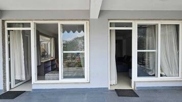 A modern building with large sliding glass doors leading to a balcony with a view of a mountainous landscape.