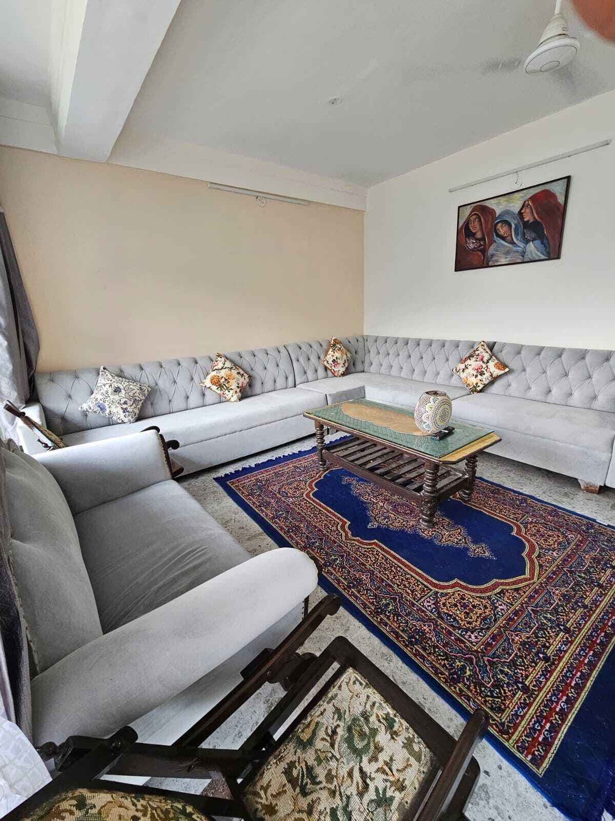 A living room with a grey sofa, a patterned rug, and a painting on the wall.