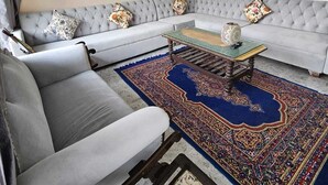 A living room with a grey sofa, a patterned rug, and a painting on the wall. - Sukon House by Crimson Horizon (Mussoorie)