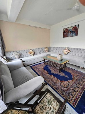 A living room with a grey sofa, a patterned rug, and a painting on the wall.