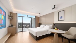 Ein Hotelzimmer mit einem Bett, einem runden Tisch, einem Stuhl, einem Schreibtisch und einem großen Fenster.